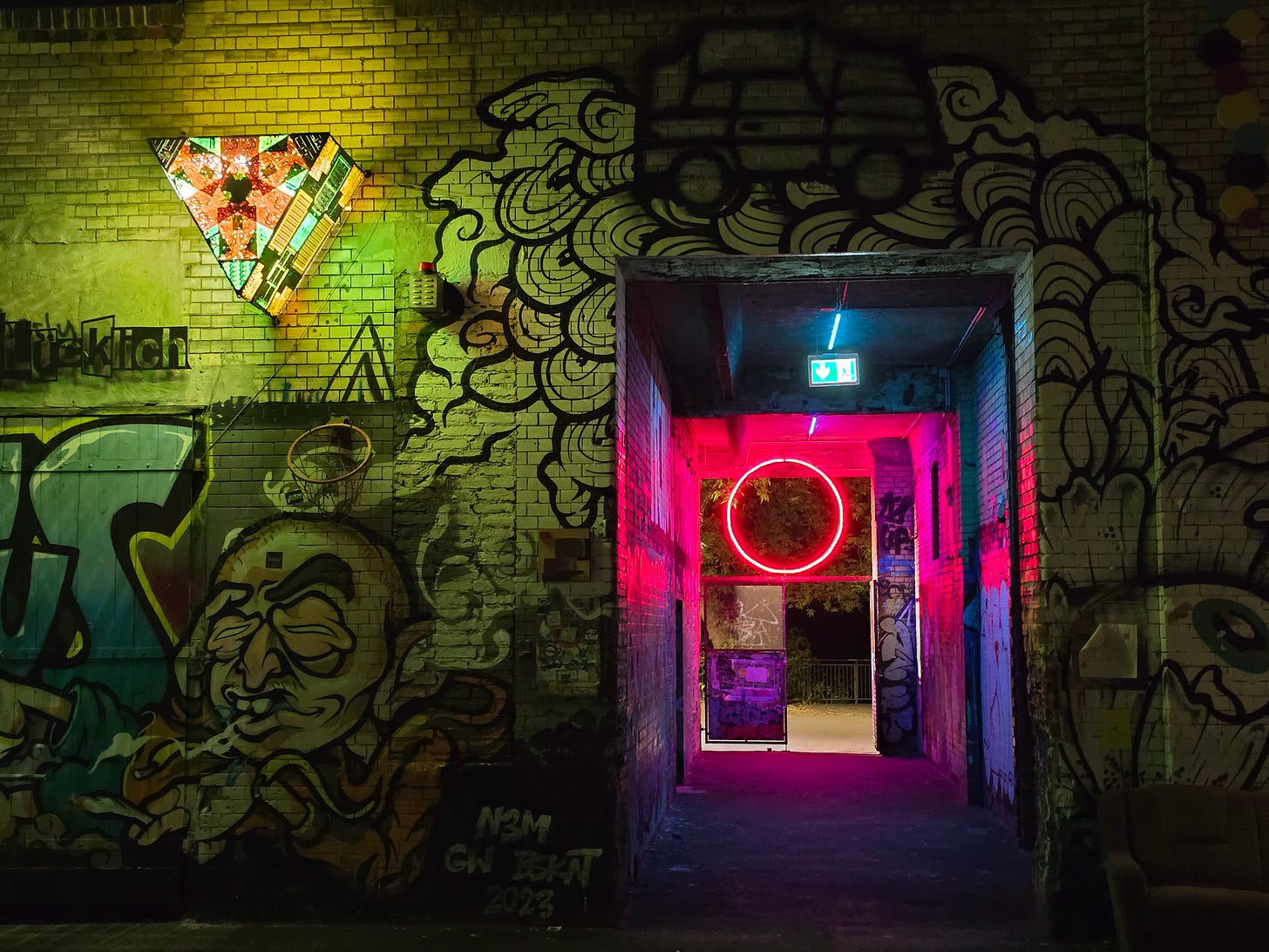 A graffiti covered wall, and neon lit passageway