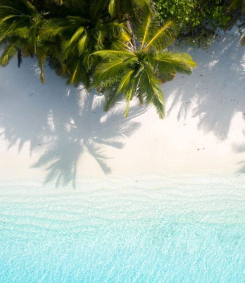 Cocos keeling islands, palm trees and crystal blue water from birds eye perspective. 