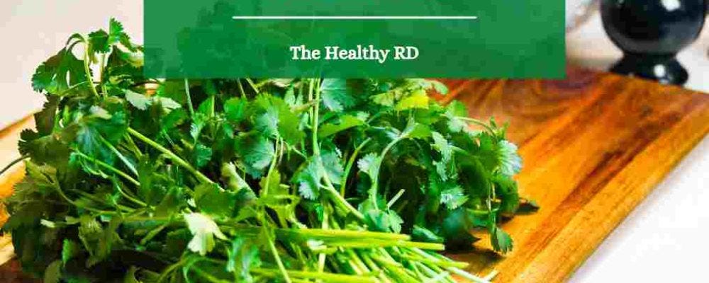 Image of fresh cilantro on a wooden cutting board with wording cilantro for heavy metal detox by The Healthy RD