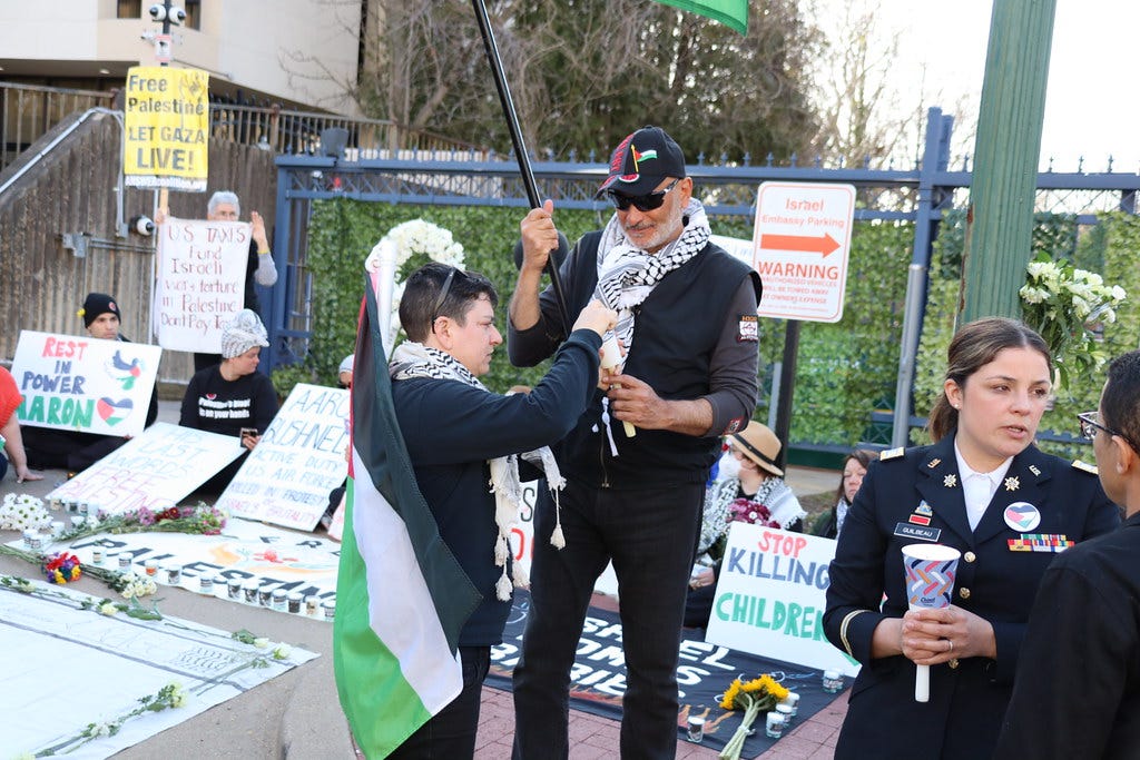 Protestors at a vigil for Aaron Bushnell, with placards and Palestinian flags on show.