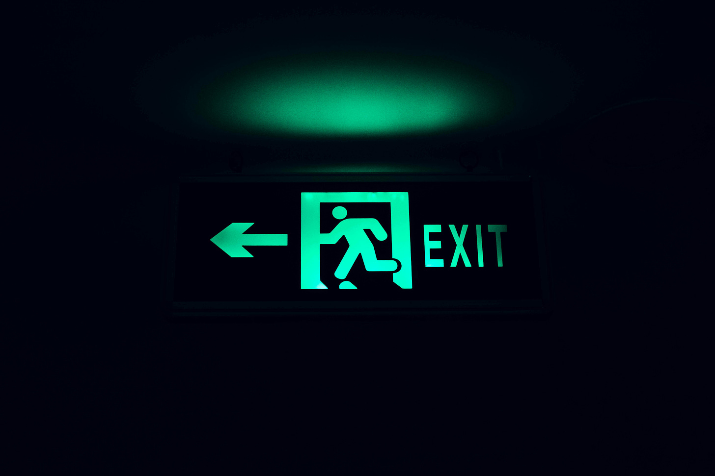 Green emergency exit sign on a black background