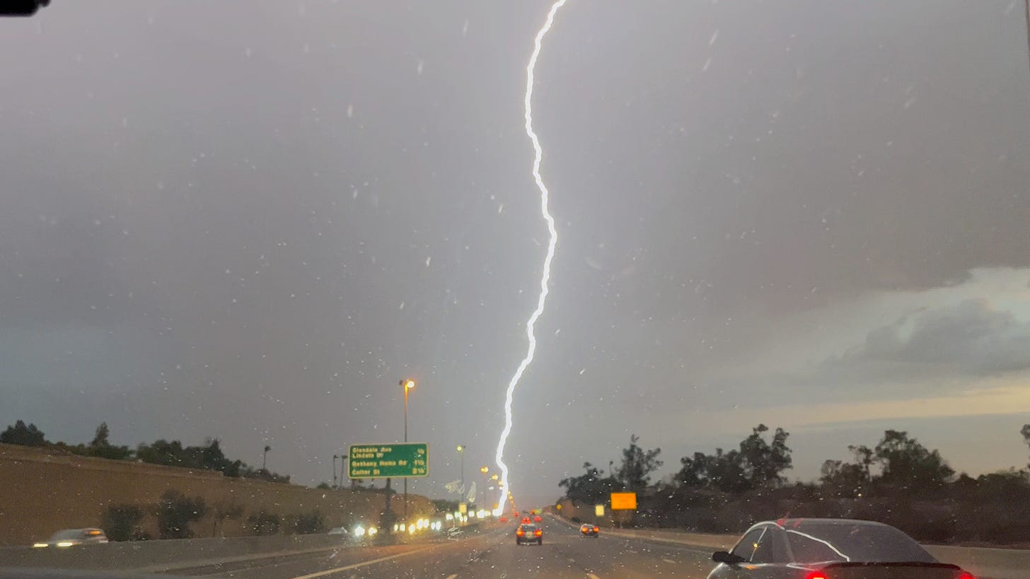 lightning strikes above the highway, one long line down the middle of the photo