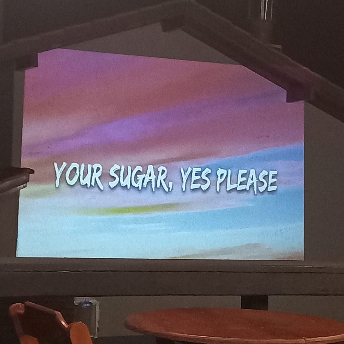 letra de sugar do maroon 5, especificamente "your sugar yes please" projetada numa parede de uma casa