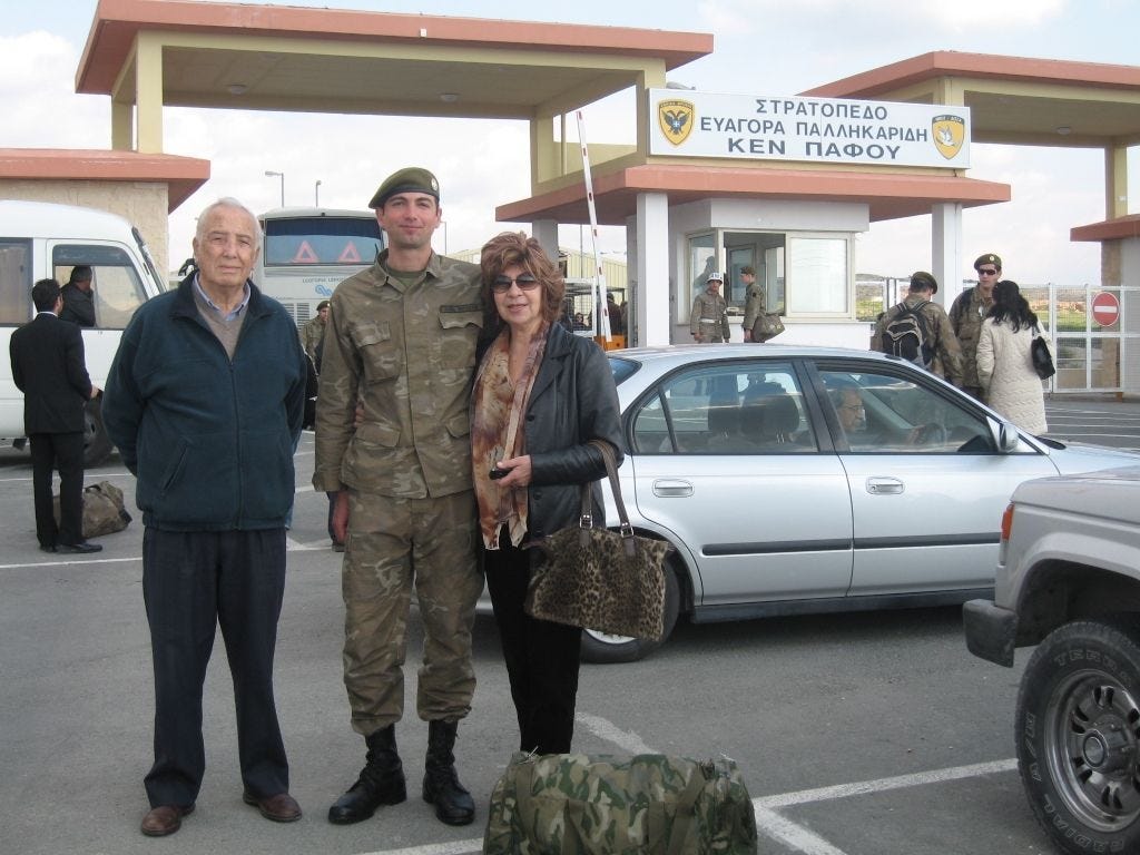 an older man and woman standing on each side of a soldier at the entrance to boot camp