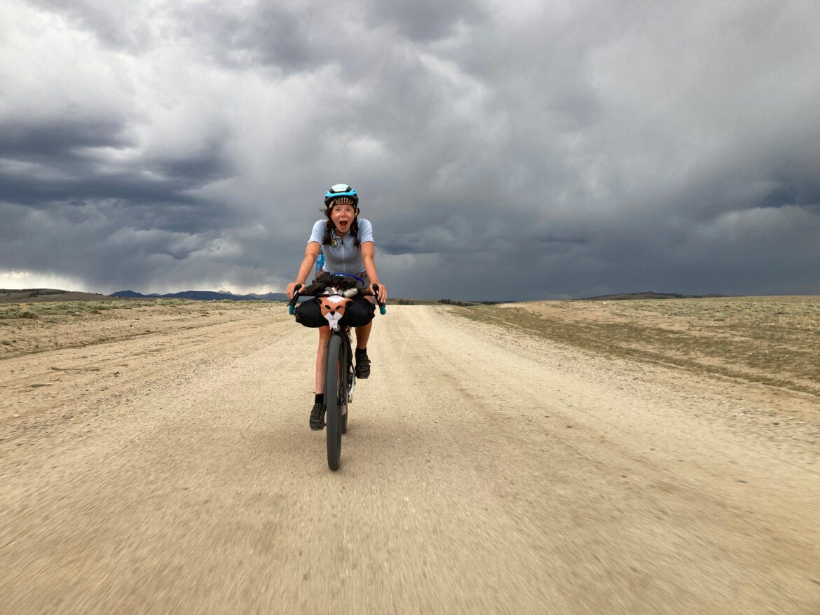 Une adolescente à vélo sur une route dans le desert.