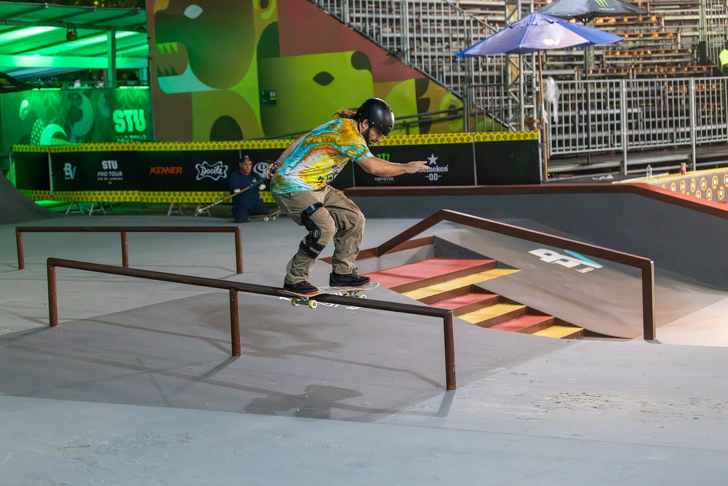 anthony ferraro wearing tie dye and a knee brace attempts a boardslide on a rail at stu pro 2024 in rio de janeiro