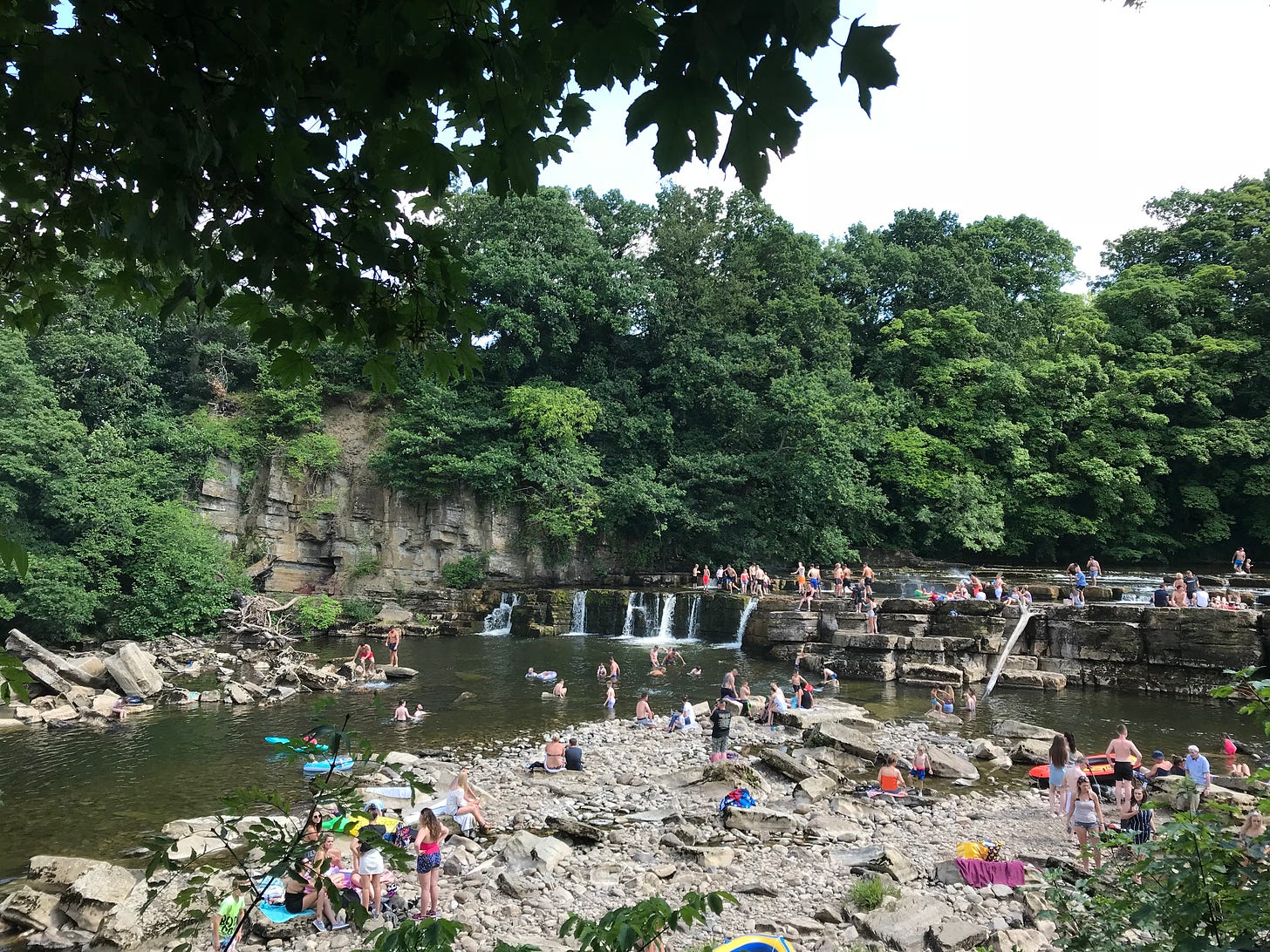 people paddling and sitting next to the river swale at the falls