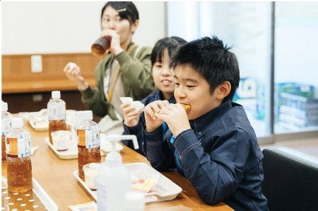 Un enfant mange goulûment son repas dans une cafétéria pour enfants pauvres au Japon