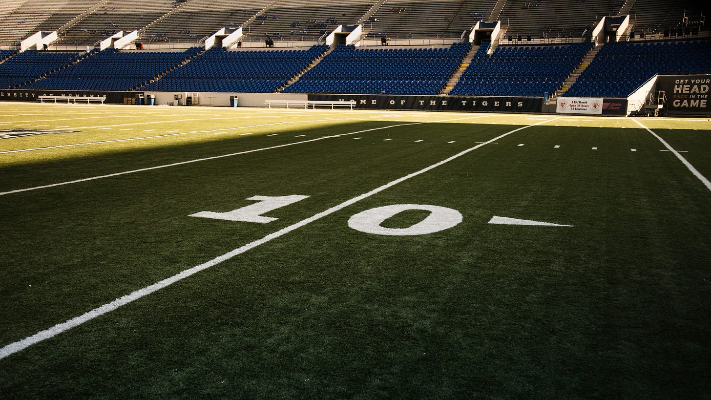 The ten yard line of a football field. 10 is in white. The field is green.