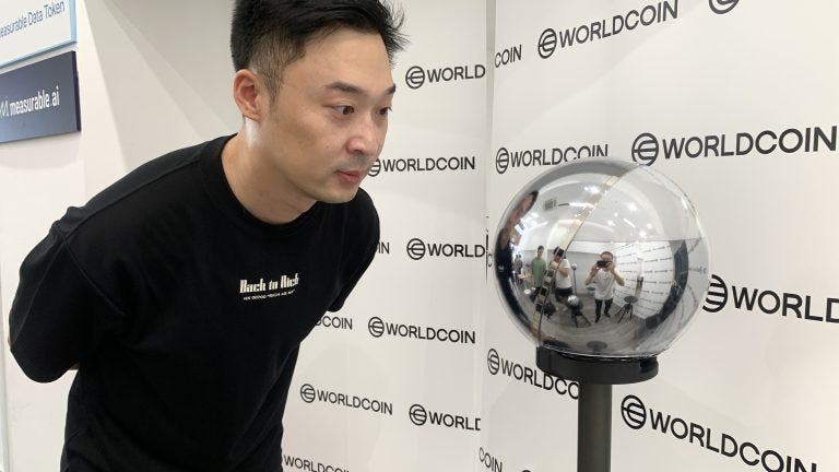 A photo showing a man staring intently into a silver orb.