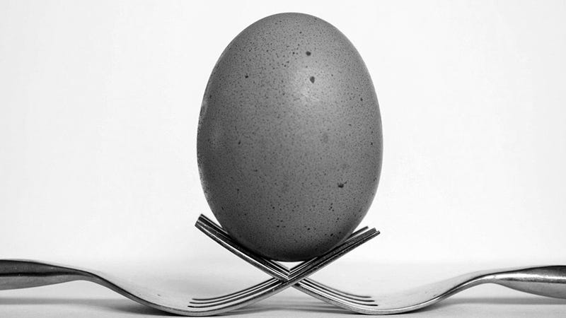 Two forks interlock their tines to balance an egg