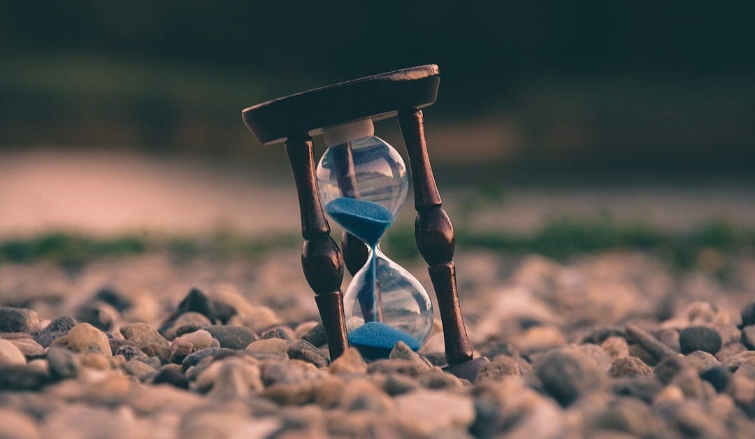 selective focus photo of brown and blue hourglass on stones