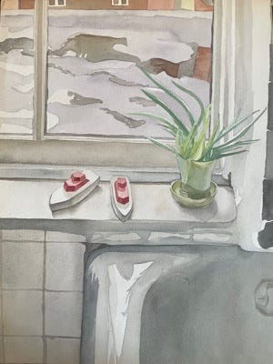 Two toy boats, one larger than the other, on a windowsill in a bathroom with an aloe plant and the corner of a bathtub visible.