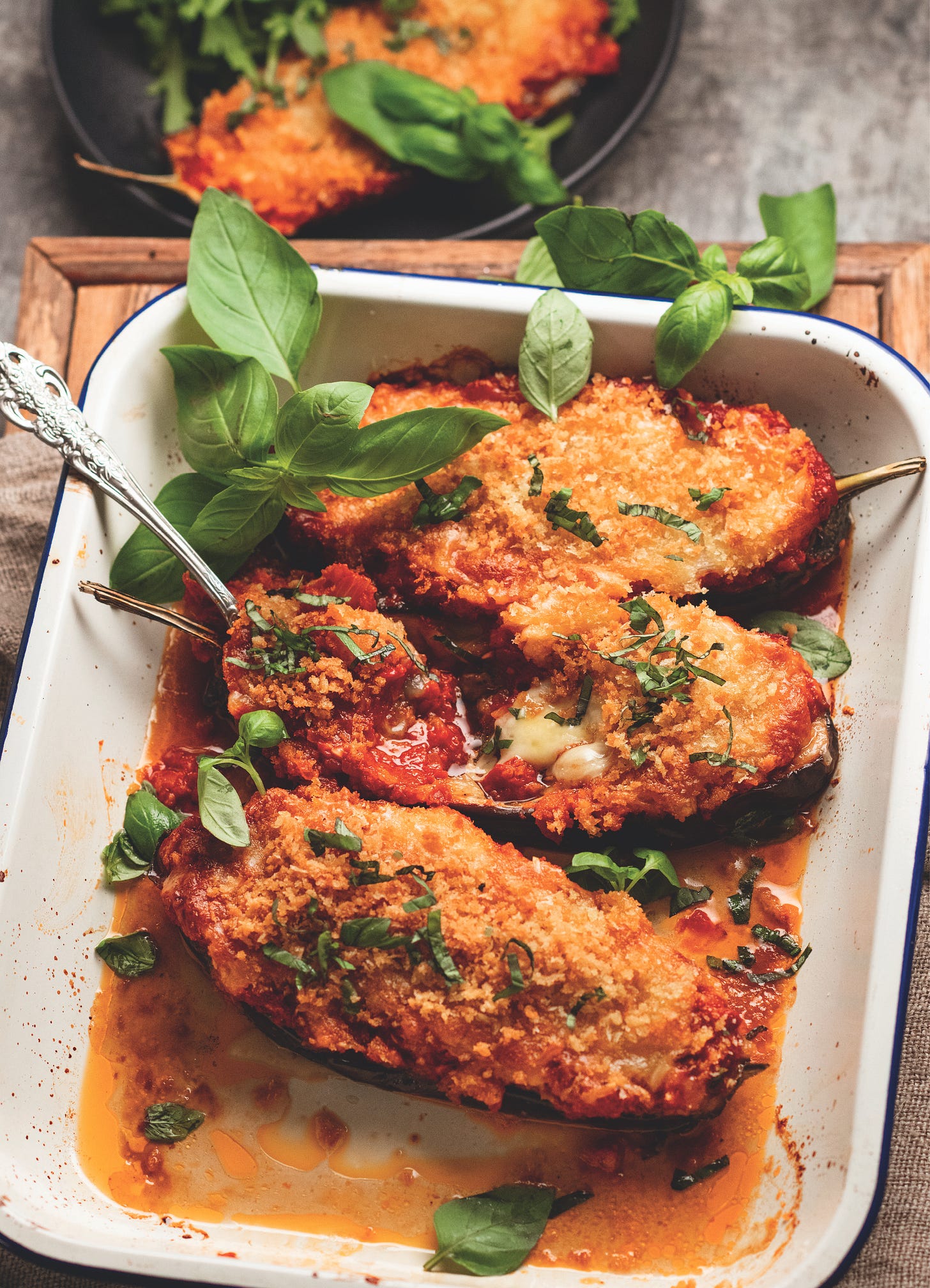 Eggplant halves in a white baking dish with crispy topping