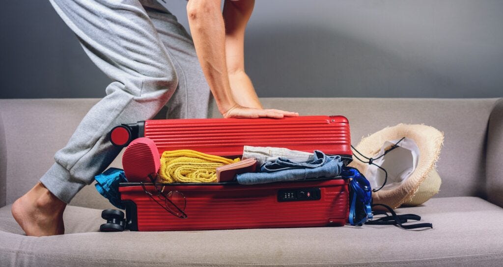 woman packing red suitcase to travel in coronavirus COVID 19