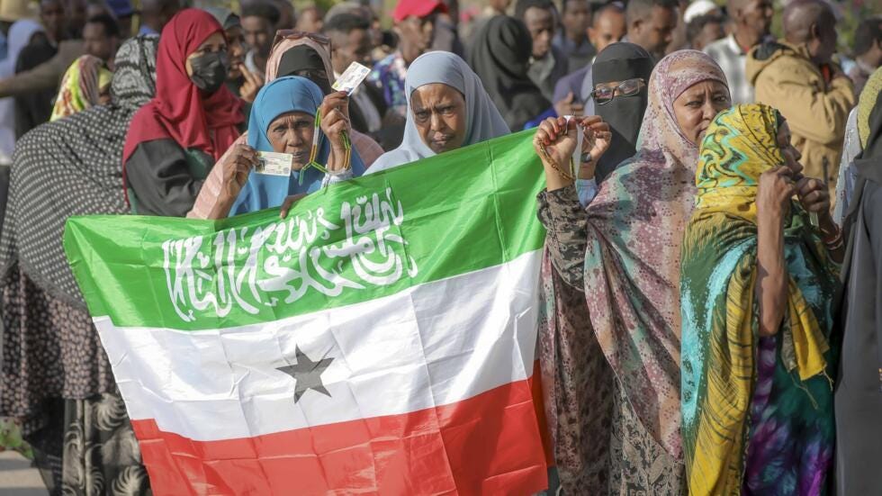 A woman displays the Somaliland flag as people queue to cast their votes during the 2024 presidential election in Hargeisa, on 13 November, 2024.