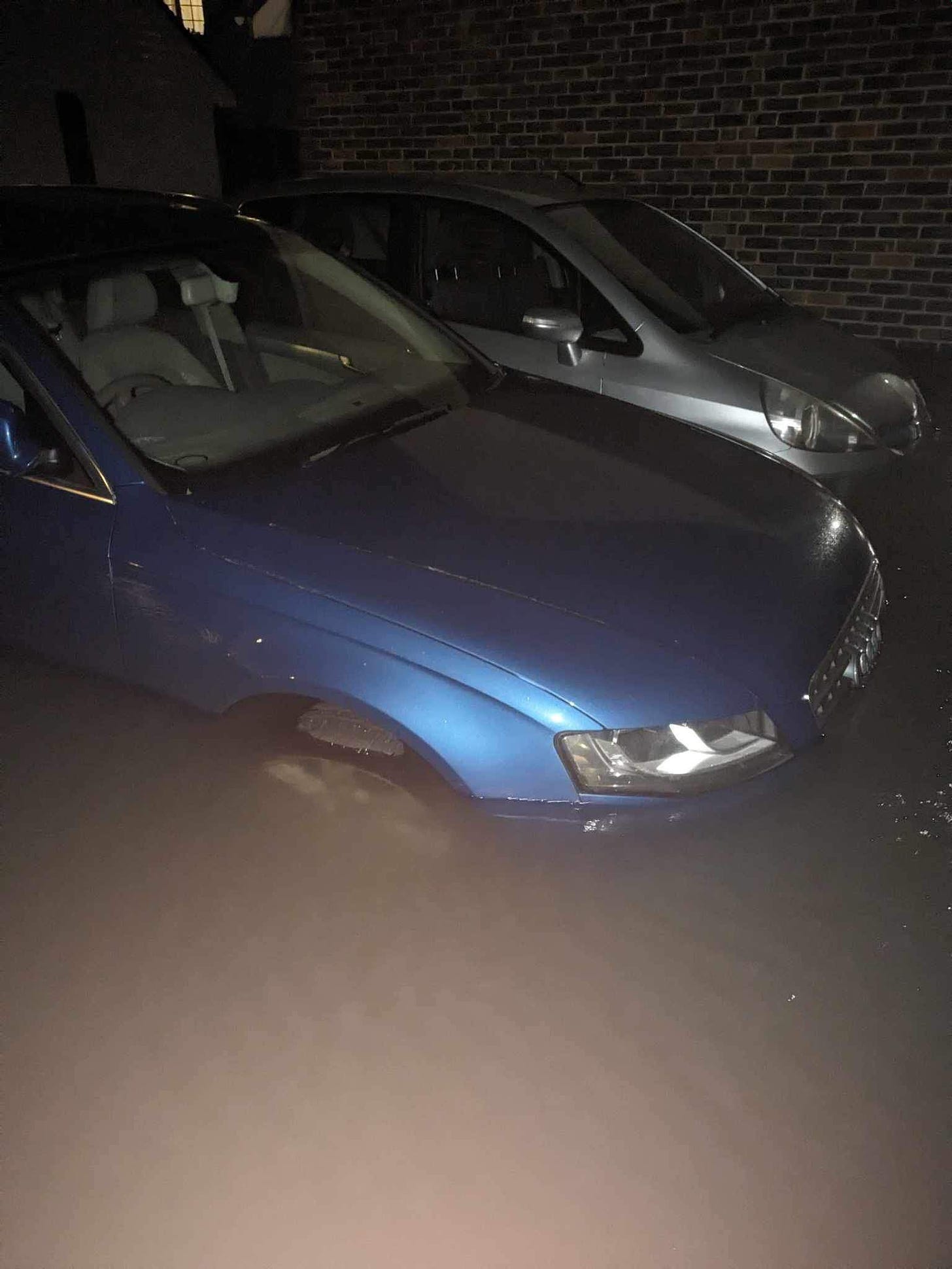 A car submerged in water up to the top of its front tyre