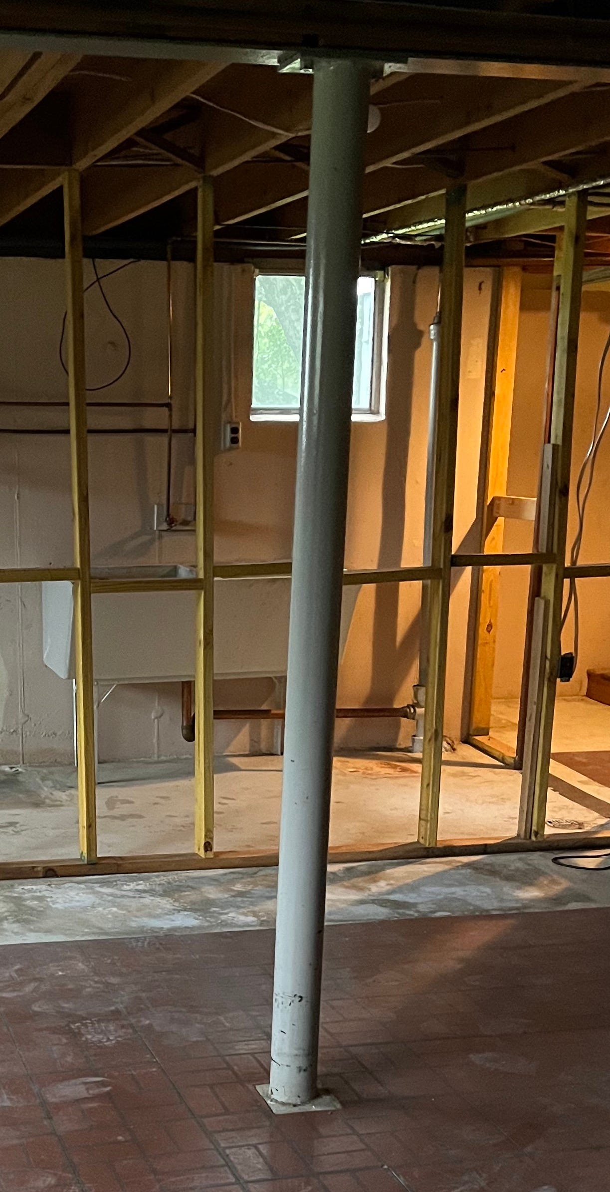 Painted round gray metal column in an under construction basement.