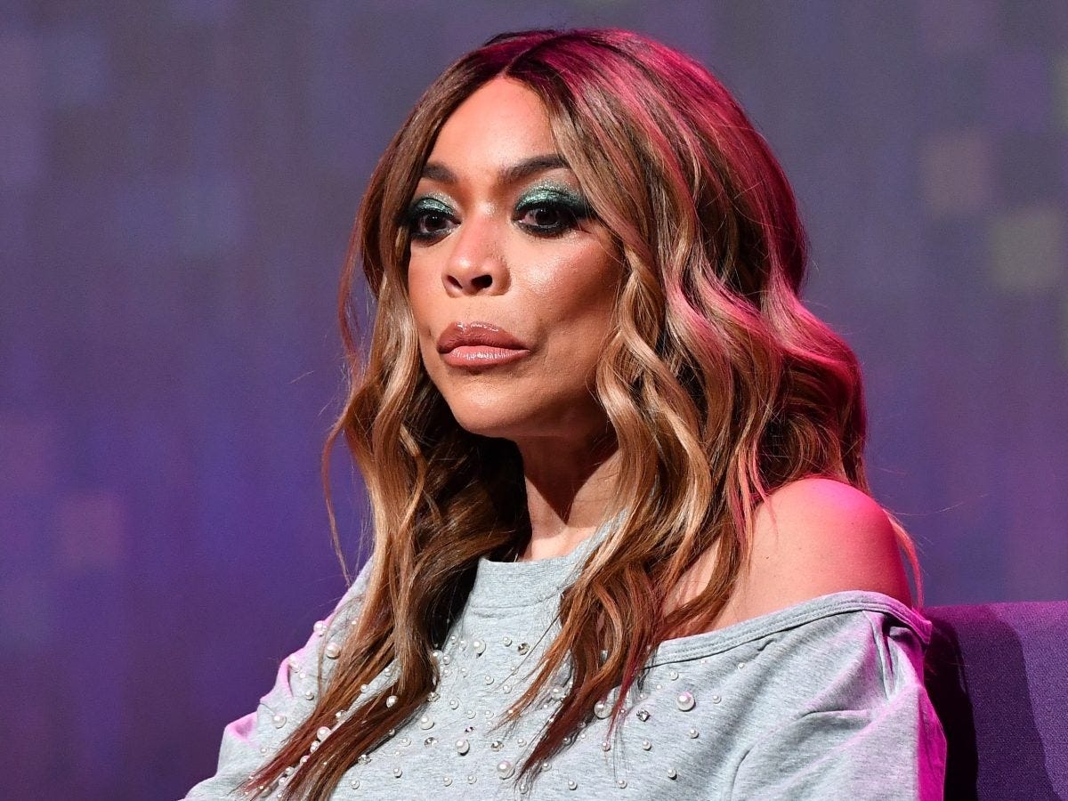 A photo of a Black woman with wavy hair and green eyeshadow as she stares into the middle distance.