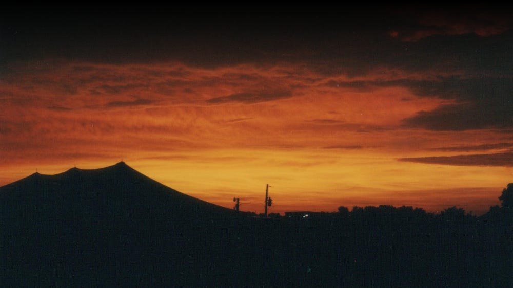 Orange sunset with silhouette of tents in the foreground