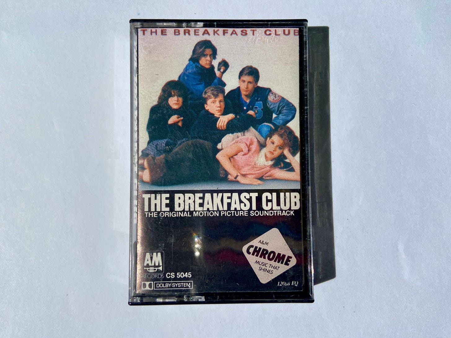 the jewel case for The Breakfast Club movie soundtracks shows five teenagers staring and posing next to each other under red text.