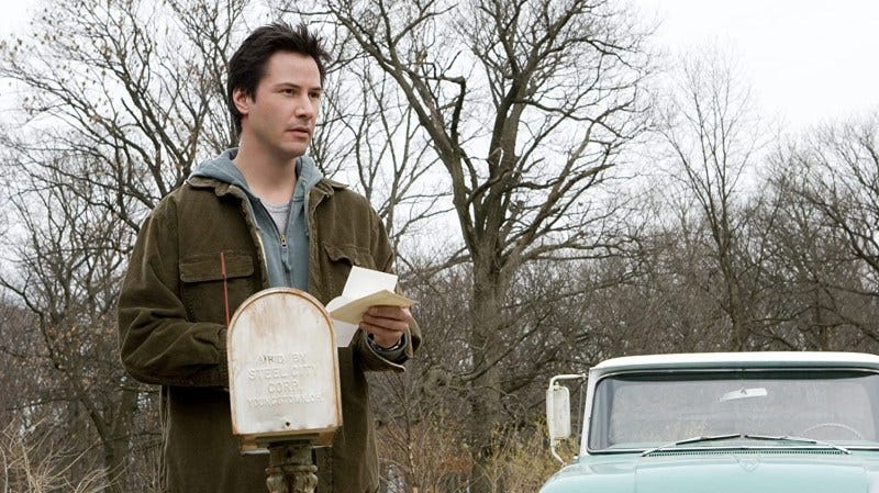Keanu Reeves from The Lake House. Standing by the mailbox, looking at something off camera with an open letter in his hands.