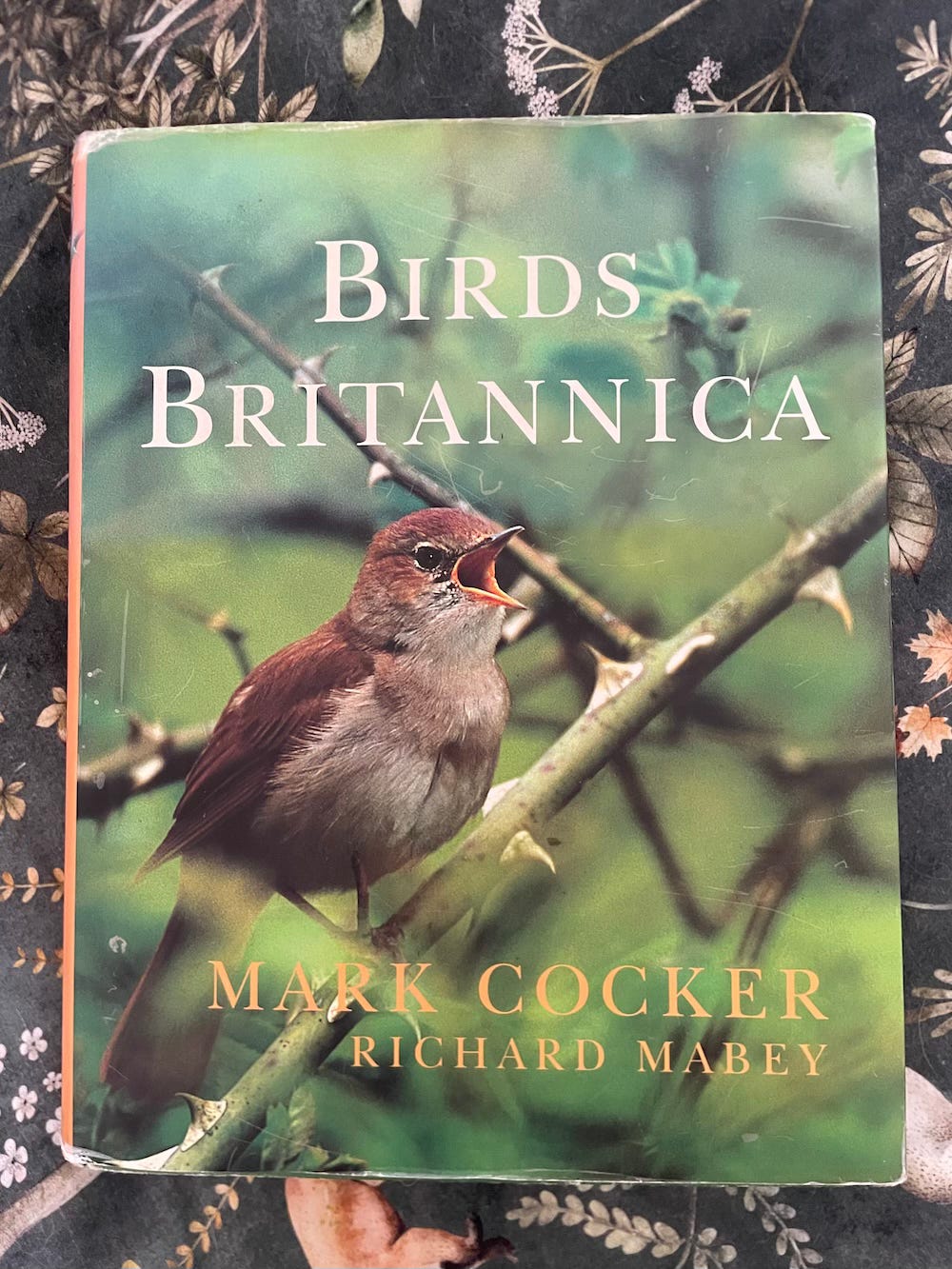 Cover of Birds Britannica featuring a nightingale singing against a green background