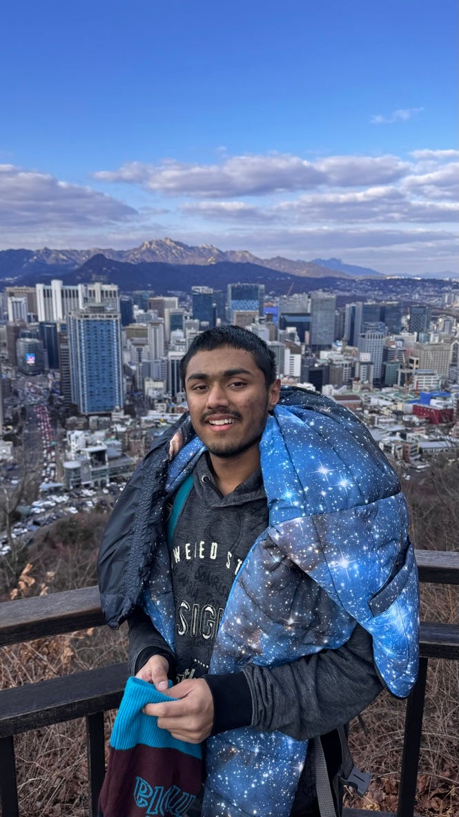 A person standing on a railing with a city in the background

Description automatically generated