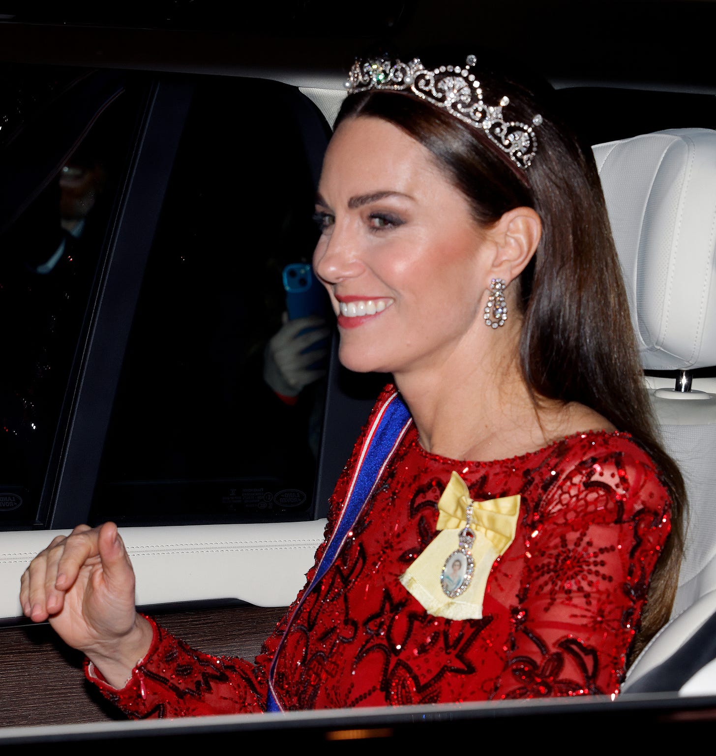 Princess Kate in  car wearing a red dress and tiara