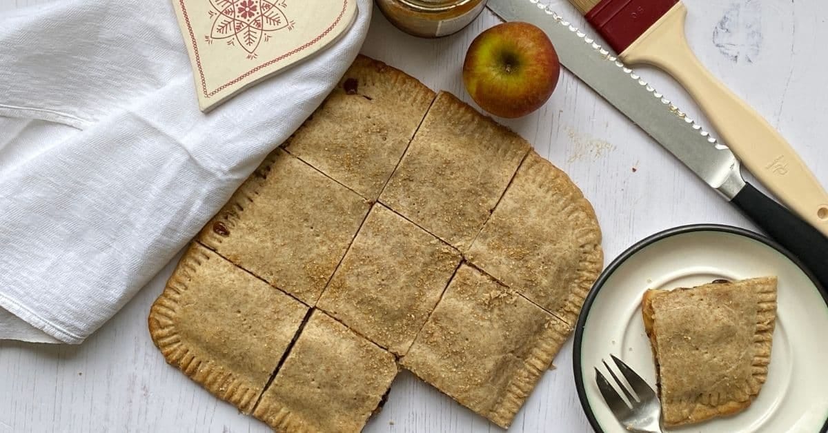 Mincemeat squares on a counter top with a slice cut out. 