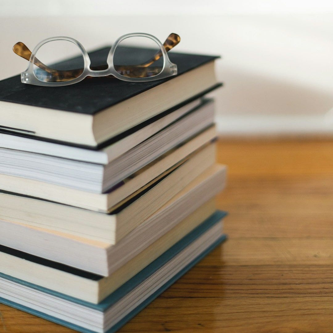 clear framed eyeglasses on top of pile of books