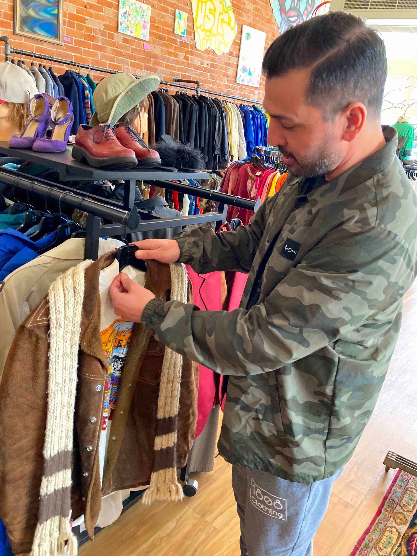 Tony inspects tee shirt on leather jacket hanging on rack