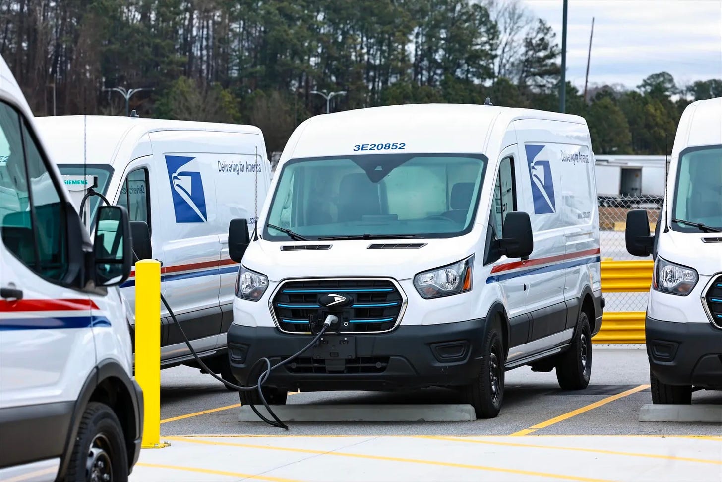A Ford E-Transit van in Postal Service livery recharges.