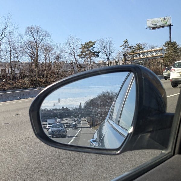 Driver-side mirror with oncoming traffic visible.