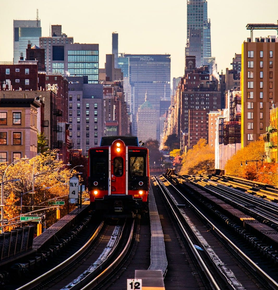 a red train traveling down train tracks next to tall buildings