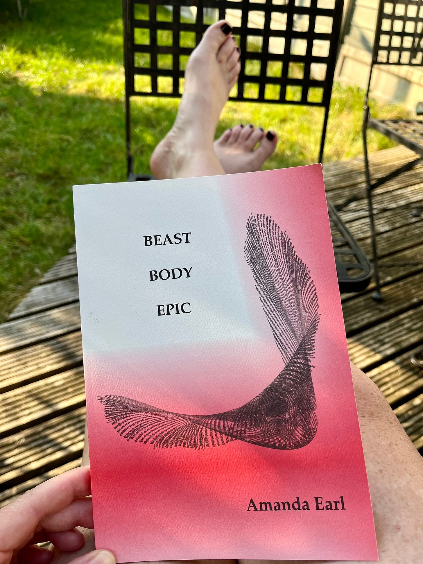 pained toenails and feet peek out beneath Beast Body Epic, a book with a red and white cover and a visual poem design