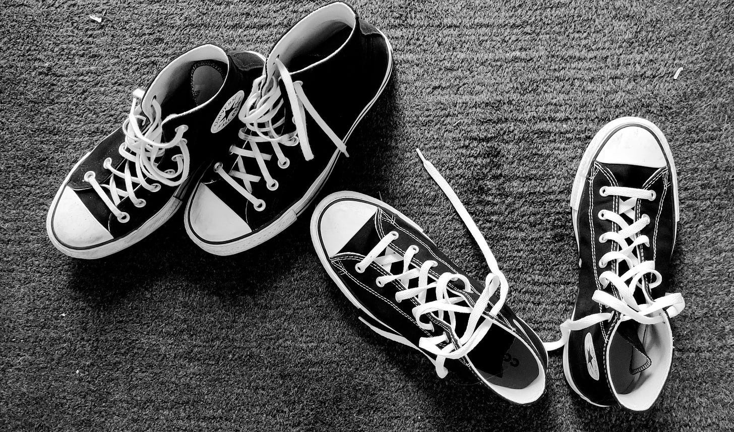 two pairs of black and white trainers on a grey carpet