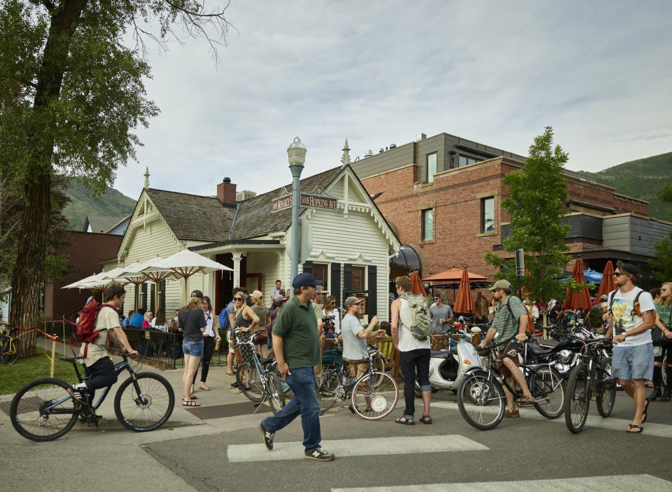 A town square in front of several low story restaurants features a crowd of people with bicycles