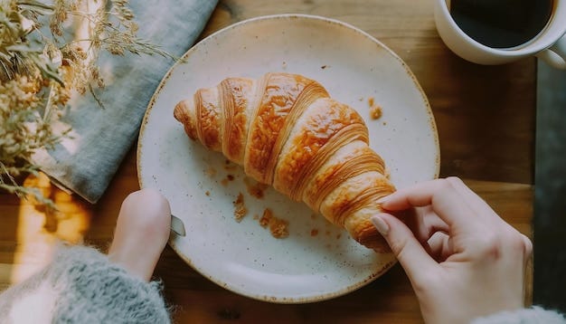 Person pulling apart yummy homemade baked croissant on plate near cup of  coffee at table | Premium AI-generated image