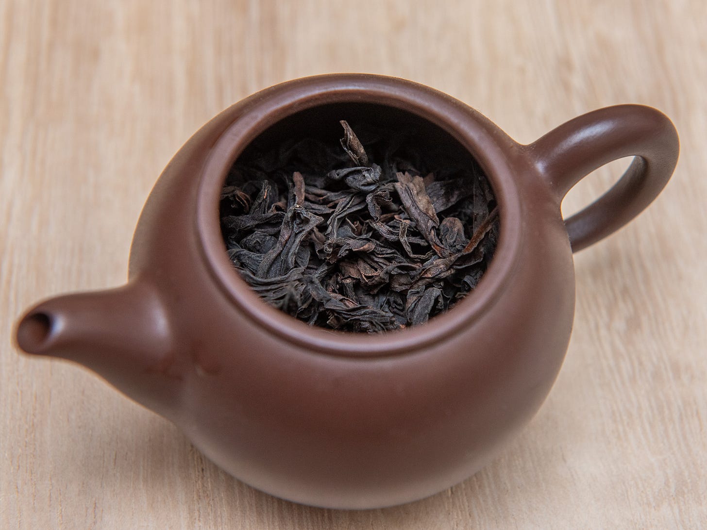 ID: Brown clay teapot half filled with dry rou gui leaves