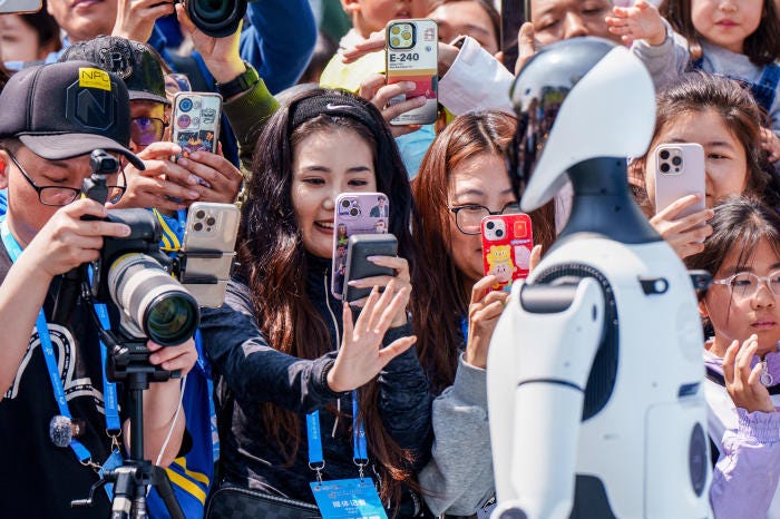 Crowd of people taking photos of a humanoid robot at a half-marathon.