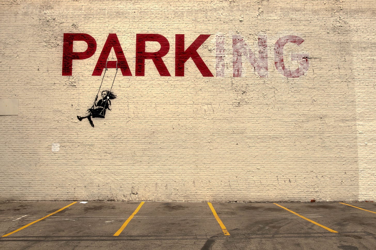 Banksy's "Swing Girl" 2010 mural in Los Angeles on a wall over a parking lot of a girl swinging from the A of the word PARKING and with the ING faded out so it mainly reads PARK