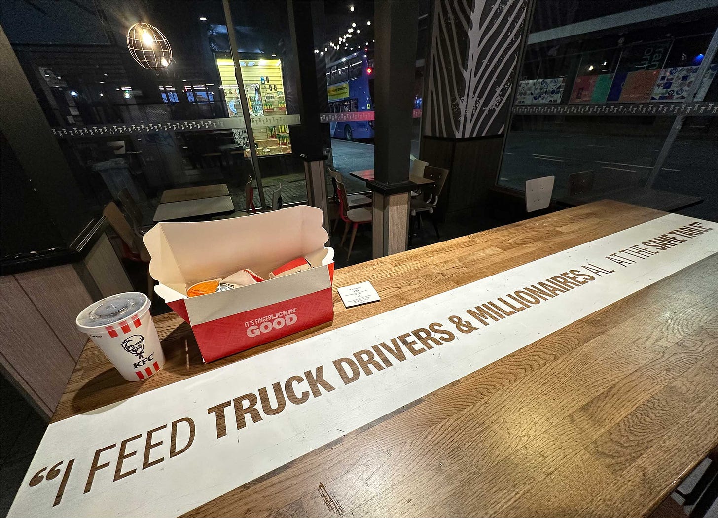 Quote displayed across table top in KFC restaurant at night.