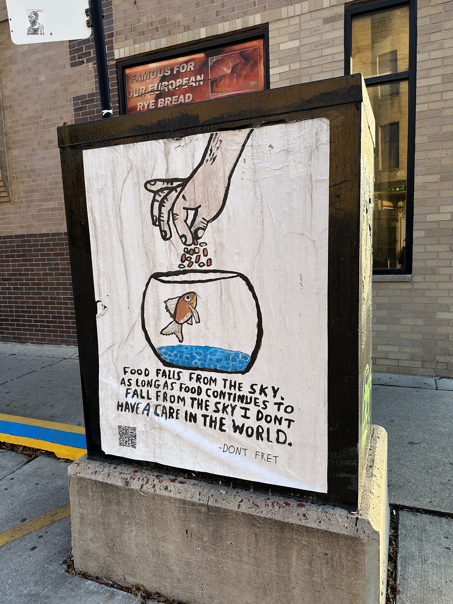 Poster in an illustrated painted style of a hand feeding a goldfish in a bowl. Underneath it says “Food falls from the sky. As long as food continues to fall from the sky I don’t have a care in the world. Don’t fret.”