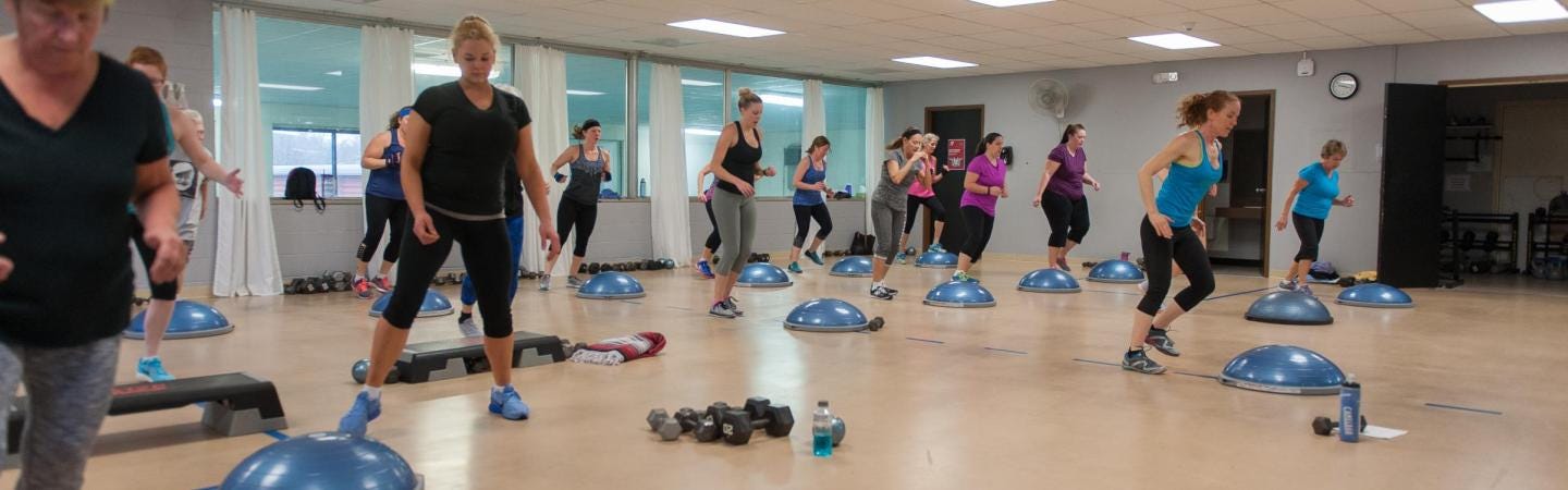 Exercise class featuring bosu balls, steps and free weights