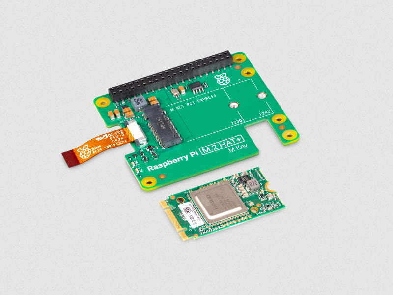 The image shows two components commonly used in conjunction with Raspberry Pi devices. The larger component on the top is a Raspberry Pi M.2 HAT+ (Hardware Attached on Top) board. It features an M.2 connector for PCI Express devices and has mounting holes labeled for different M.2 sizes (2230 and 2242). There is also a ribbon cable connector and other electronic components on the board. The smaller component at the bottom is an M.2 module, likely an NVMe SSD or a different type of PCIe device. It has a metallic shield over the main chip and a gold connector edge designed to fit into the M.2 slot on the HAT+ board. The component also shows a few smaller electronic components and traces on its PCB (Printed Circuit Board). These components are used together to expand the functionality of a Raspberry Pi by adding high-speed storage or other peripherals through the M.2 interface.