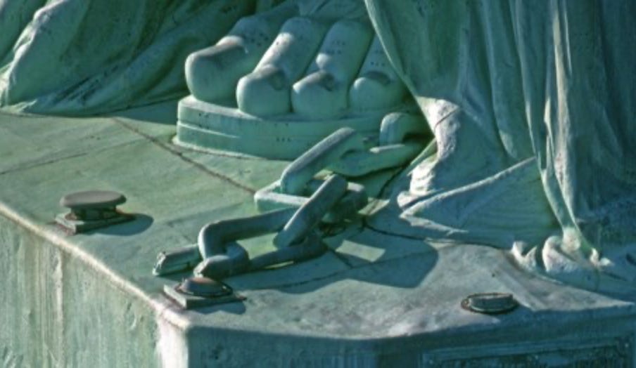 A photo of the Statue of Liberty's feet, broken chains alongside her on the platform.