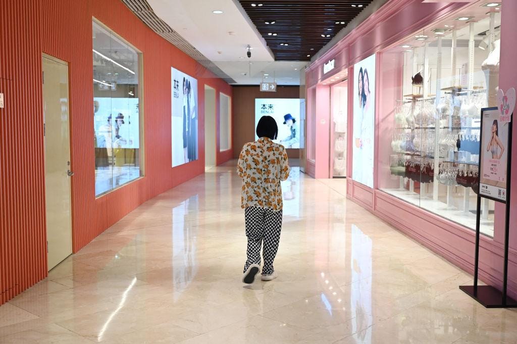 A woman walks past stores in a shopping mall in Beijing on July 18, 2023. (Greg Baker/AFP via Getty Images)