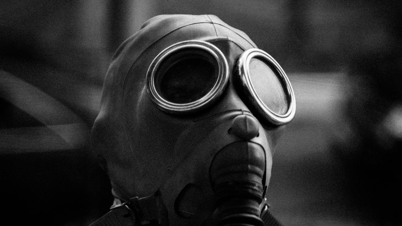 A gas mask lays against an unfocused background in black and white