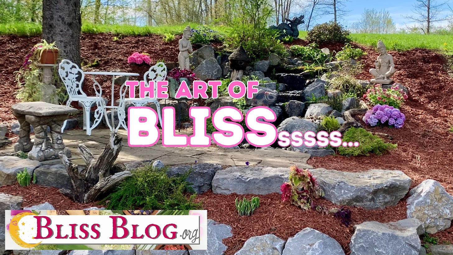 Stone patio and waterfall, flowers and small white bistro table with two chairs.